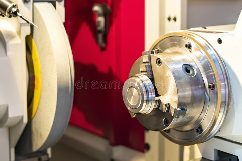 Metal cylinder or workpiece clamp by 3 jaw chuck and during surface grinding on high precision automatic cnc grinder machine with royalty free stock photography