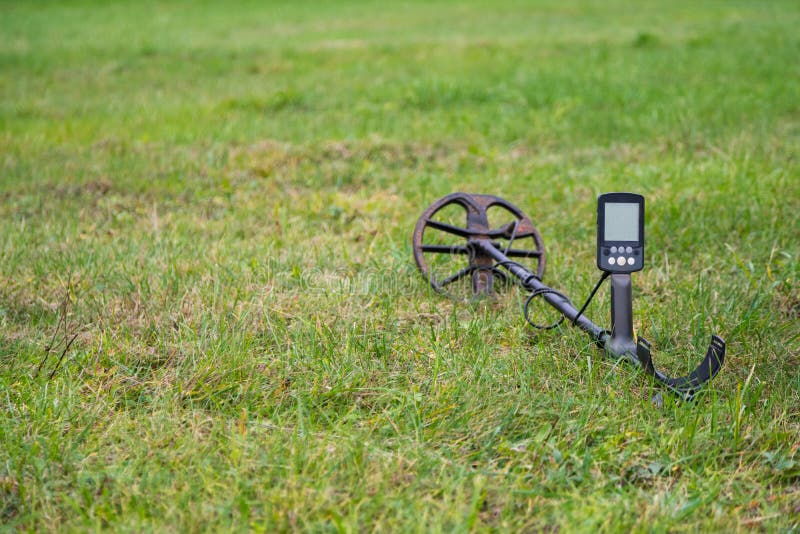 Metal detector laying outdoors on the grass. Close up electronic treasure finder. Metal detector laying outdoors on the grass. Close up electronic treasure finder.