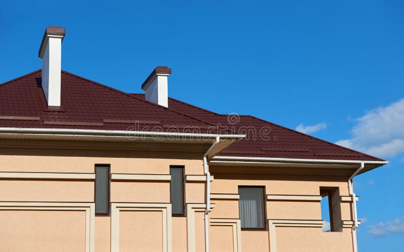 Metal el tejado y las paredes de la nueva casa privada, con las chimeneas y la ventilación en el fondo del cielo, el concepto de foto de archivo libre de regalías Metal el tejado y las paredes de la nueva casa privada, con las chimeneas y la ventilación en el fondo del cielo, el concepto de foto de archivo libre de regalías
