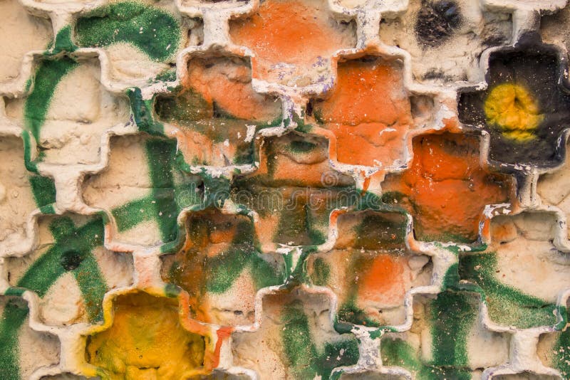 Metal grille on a white brick wall with bright yellow, orange, black and green spots and splashes of paint. rough surface texture royalty free stock photography Metal grille on a white brick wall with bright yellow, orange, black and green spots and splashes of paint. rough surface texture royalty free stock photography