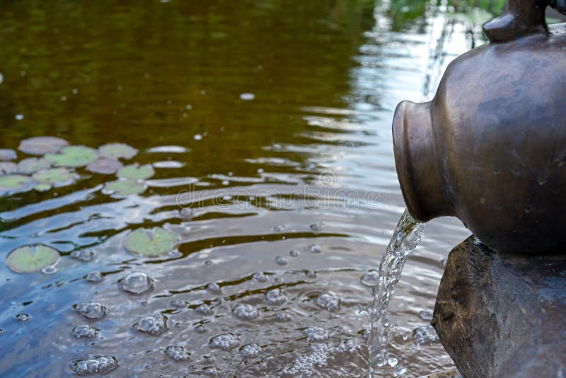 Metal Jug with Running Water Creating Circles and Bubbles Stock Image
