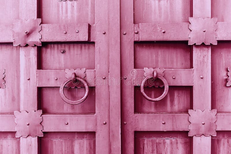 Metal la porta strutturata annata rosa con le maniglie di porta degli anelli ed i dettagli del metallo nella forma di fiori stili fotografia stock libera da diritti Metal la porta strutturata annata rosa con le maniglie di porta degli anelli ed i dettagli del metallo nella forma di fiori stili fotografia stock libera da diritti