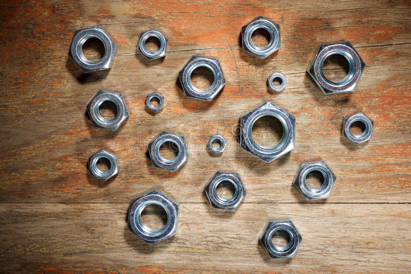 Close up of some metal nuts for fixing of fasteners on a wooden table. Close up of some metal nuts for fixing of fasteners on a wooden table