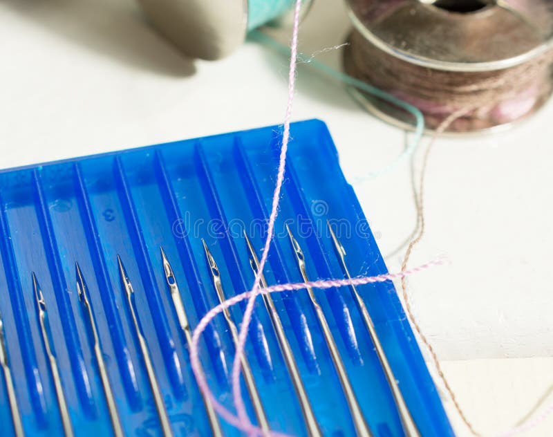 Metal Spools of Thread for a Sewing Machine and Needles in a Blue Box