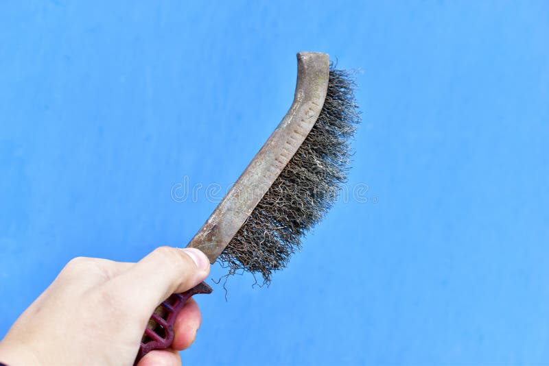 Metal Surface Cleaning Brush in Hand on a Blue Background Stock Photo