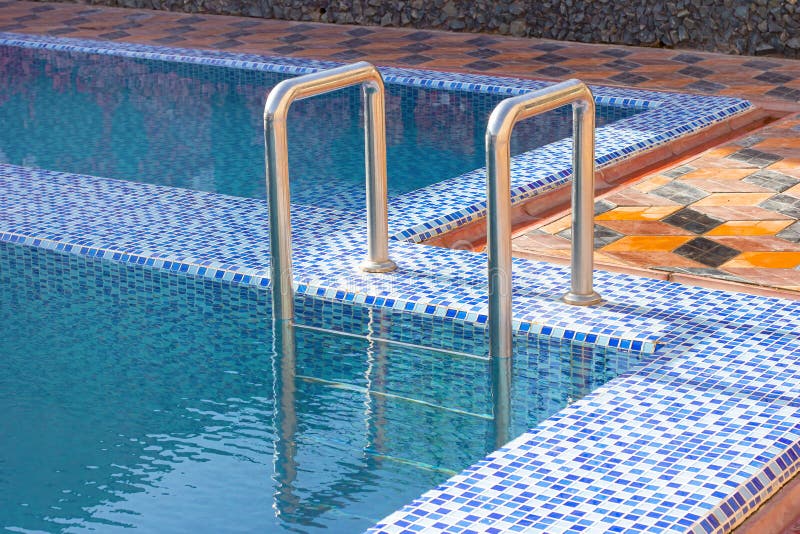 A metal swimming pool safe ladder (skimmer) on the entrance to the home inground poolside royalty free stock image A metal swimming pool safe ladder (skimmer) on the entrance to the home inground poolside royalty free stock image