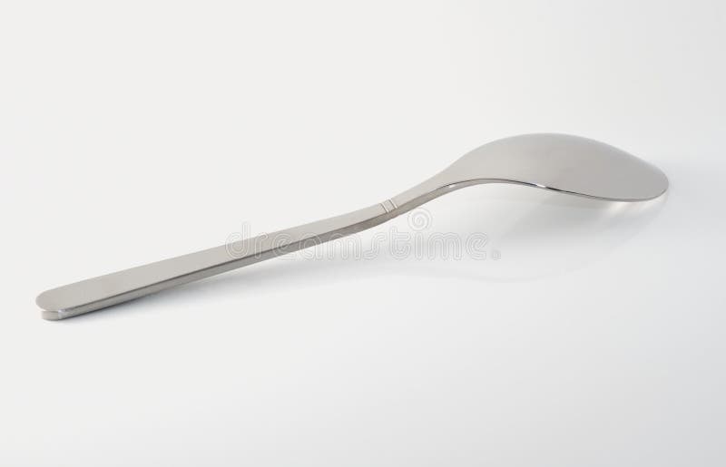 Metal teaspoon on white specular surface