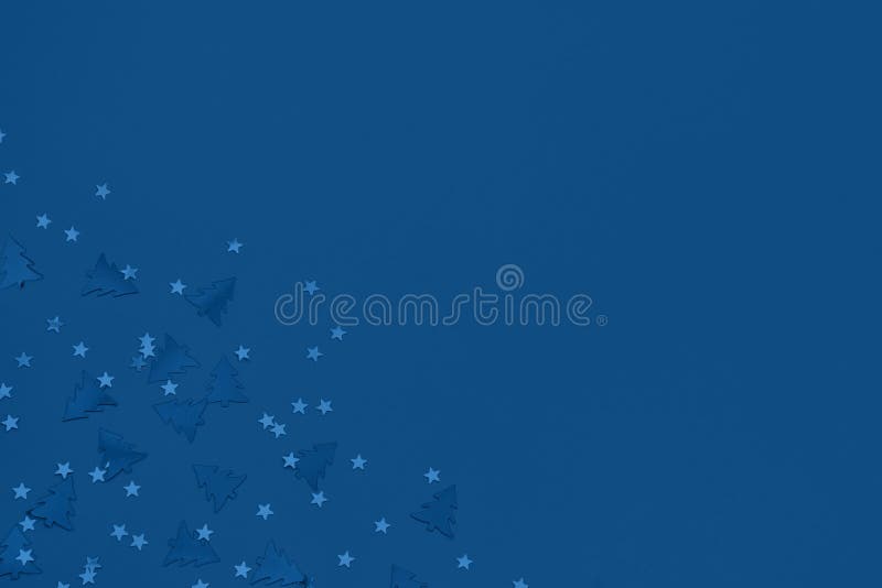 Metallic foil christmas trees and stars confetti sparse on trendy blue background