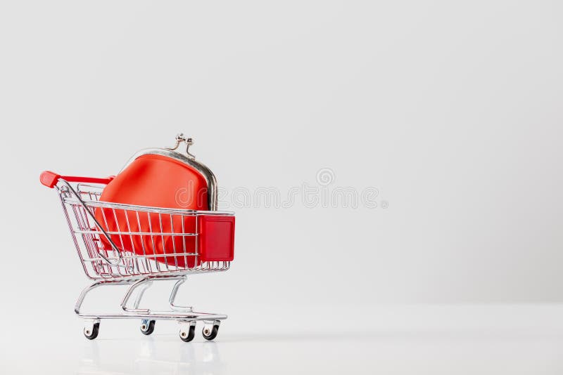 Metallic shopping cart trolley and Red Coin Purse on light gray background with copy space royalty free stock image