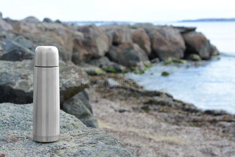 Aluminium Thermos with Hot Drink on Rock Stone Outdoors. Space for