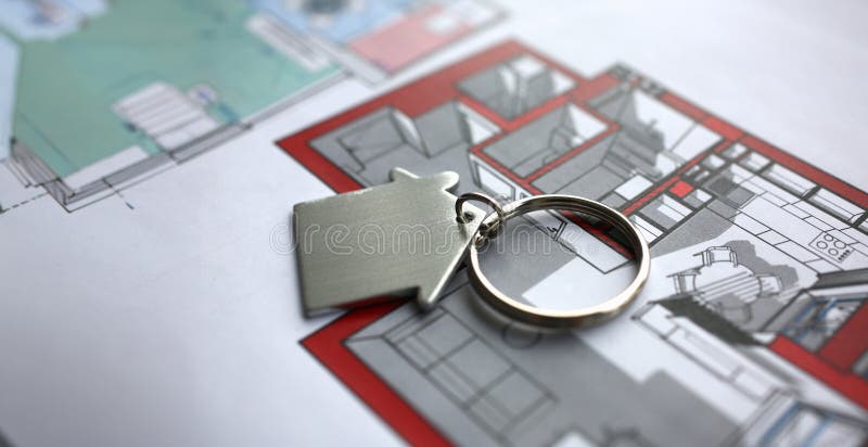 Metal key chain in form miniature house lies on paper project of apartment concept closeup. Metal key chain in form miniature house lies on paper project of apartment concept closeup