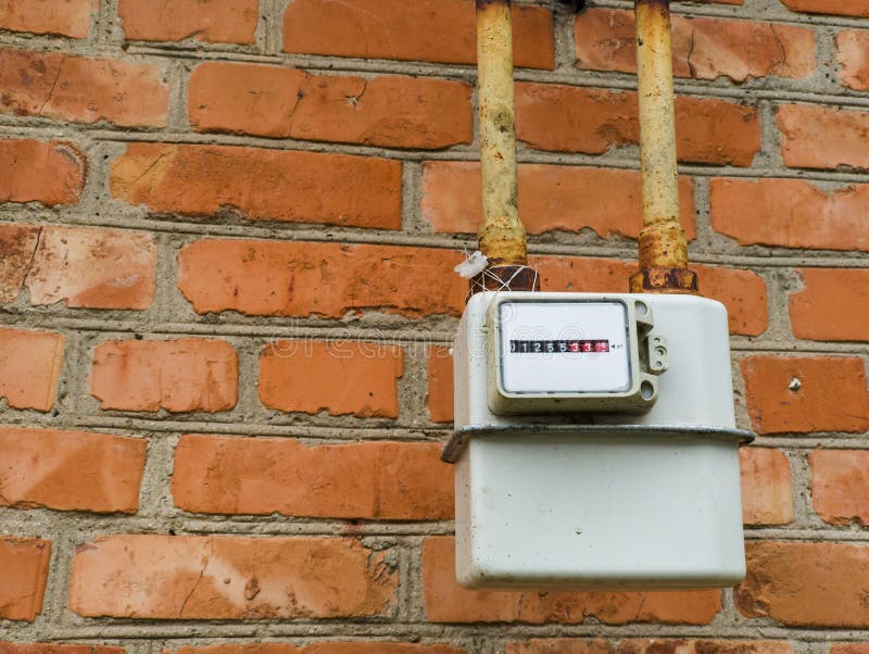 A meter on a brick wall with a yellow pipe stock images