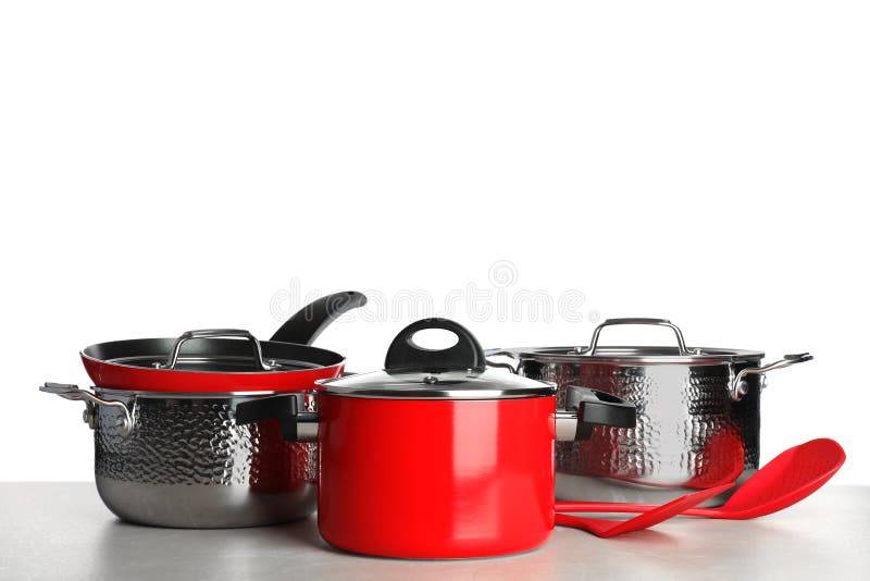Metta delle pentole e degli utensili puliti sulla tavola contro fondo bianco immagini stock Metta delle pentole e degli utensili puliti sulla tavola contro fondo bianco immagini stock