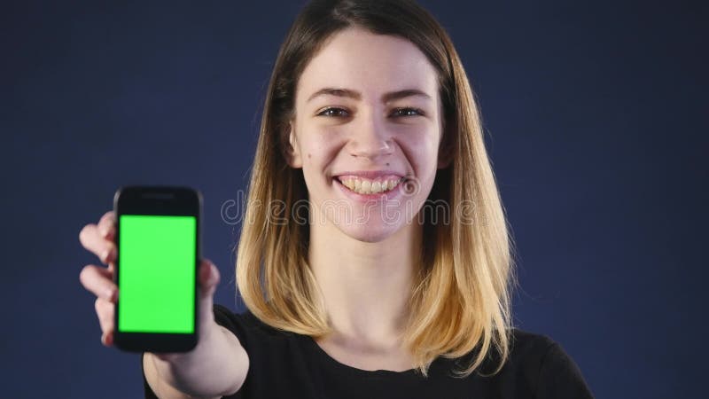 Metta a fuoco sul telefono cellulare La giovane donna passa la mostra dello schermo in bianco dello smartphone isolato su fondo v video d archivio Metta a fuoco sul telefono cellulare La giovane donna passa la mostra dello schermo in bianco dello smartphone isolato su fondo v video d archivio