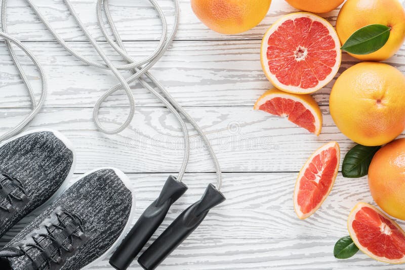 Sport shoes, rope and fresh grapefruits on rustic white wooden table, fitness accessories. Concept of healthy lifestyle, slimming, dieting and healthy nutrition. Top view, flat lay. Sport shoes, rope and fresh grapefruits on rustic white wooden table, fitness accessories. Concept of healthy lifestyle, slimming, dieting and healthy nutrition. Top view, flat lay.