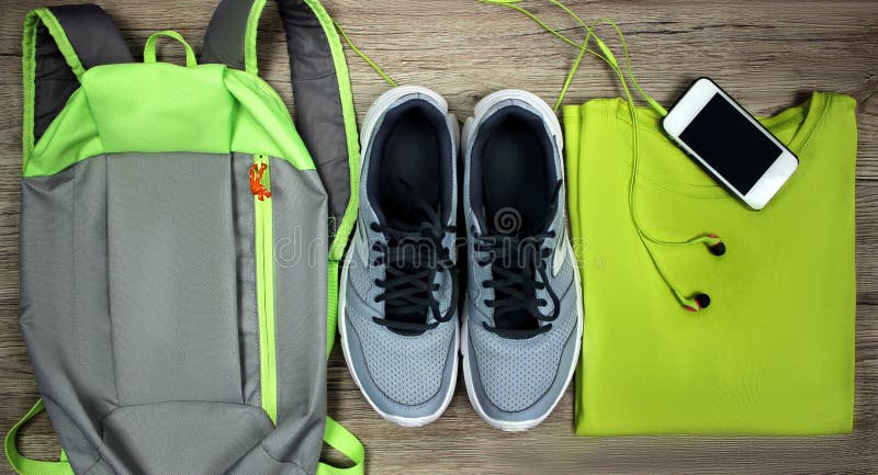Metta per le scarpe di sport, lo zaino, la maglietta, telefono cellulare con il primo piano su un fondo di legno, vista superiore fotografie stock libere da diritti Metta per le scarpe di sport, lo zaino, la maglietta, telefono cellulare con il primo piano su un fondo di legno, vista superiore fotografie stock libere da diritti