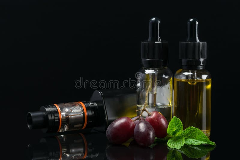 Metta per vaping con l'aroma dell'uva in bottiglie, su un fondo scuro immagine stock libera da diritti Metta per vaping con l'aroma dell'uva in bottiglie, su un fondo scuro immagine stock libera da diritti