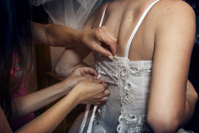 Putting wedding dress on with the help of second person. Putting wedding dress on with the help of second person