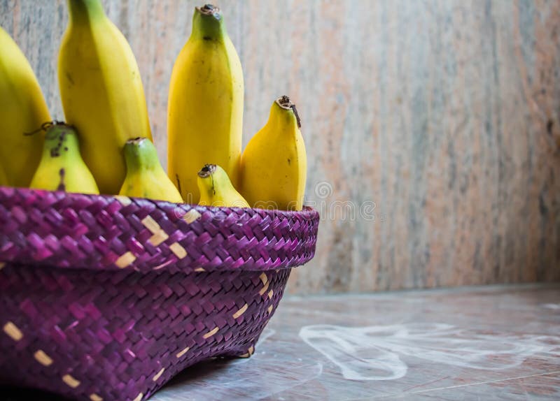 Mettez la banane à l'intérieur du panier pourpre tissé des roseaux placés sur images stock Mettez la banane à l'intérieur du panier pourpre tissé des roseaux placés sur images stock