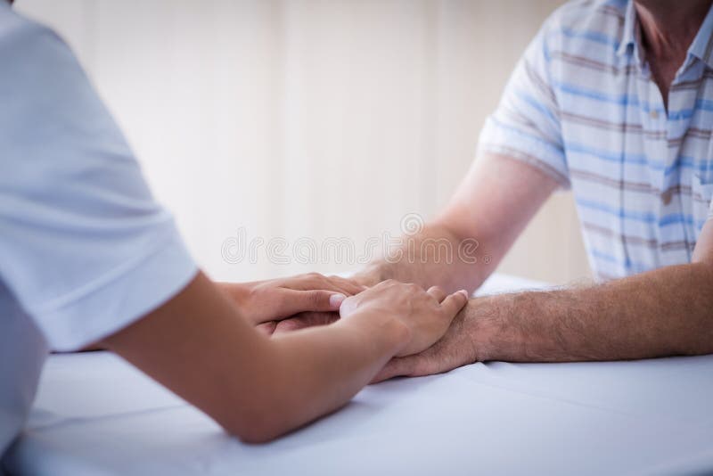Metà di sezione di medico femminile che consola uomo senior in salone fotografia stock Metà di sezione di medico femminile che consola uomo senior in salone fotografia stock