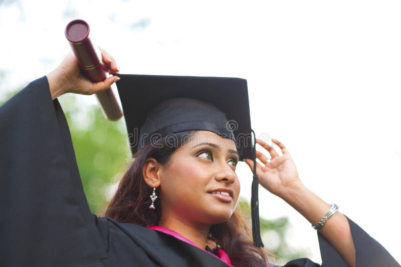 Young Asian Indian female student adjusting her graduate hat. Young Asian Indian female student adjusting her graduate hat