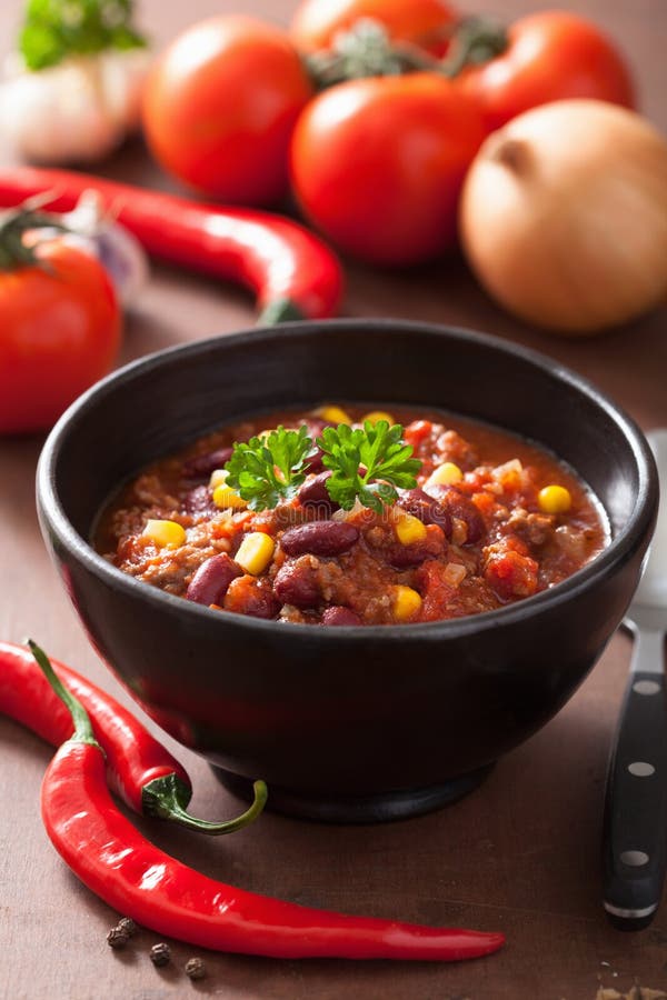 Mexican chili con carne in a black plate with ingredients. Mexican chili con carne in a black plate with ingredients