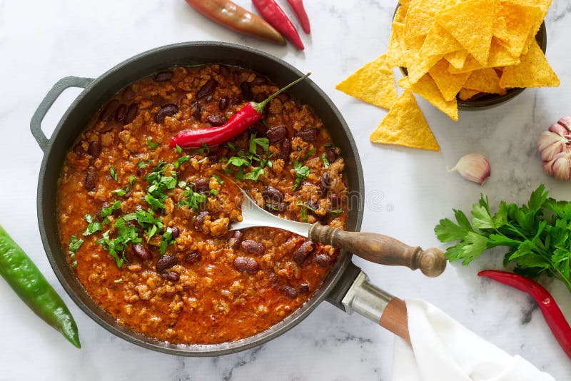 Mexican and American food Chili con carne served with nachos, pepper and herbs. Selective focus. Mexican and American food Chili con carne served with nachos, pepper and herbs. Selective focus.