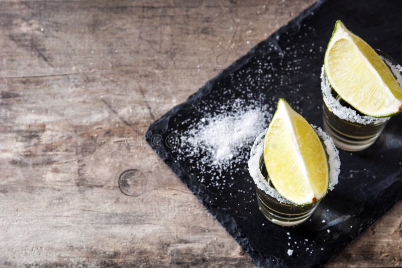 Mexicaanse Gouden Tequila met kalk en zout op houten lijst royalty-vrije stock foto's Mexicaanse Gouden Tequila met kalk en zout op houten lijst royalty-vrije stock foto's
