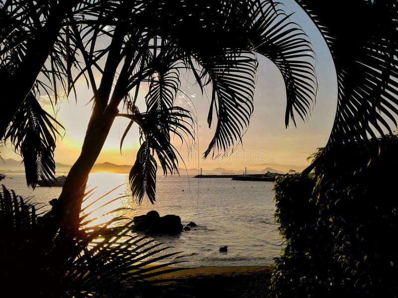 The sun rises over Manzanillo Bay with palm trees at Las Hadas Resort in Manzanillo, Colima, Mexico. The sun rises over Manzanillo Bay with palm trees at Las Hadas Resort in Manzanillo, Colima, Mexico