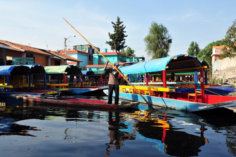 Mexicansk man som seglar färgrika mexicanska gondoler på Xochimilcos som svävar trädgårdar nära Mexico - stad, Mexico royaltyfri fotografi Mexicansk man som seglar färgrika mexicanska gondoler på Xochimilcos som svävar trädgårdar nära Mexico - stad, Mexico royaltyfri fotografi