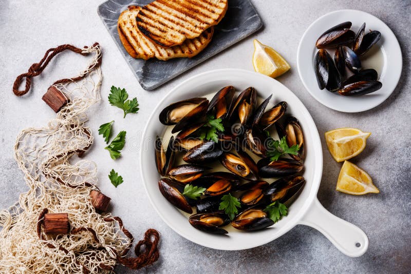 Mexilhões em cozinhar a bandeja, o pão brindado e a rede de pesca foto de stock Mexilhões em cozinhar a bandeja, o pão brindado e a rede de pesca foto de stock