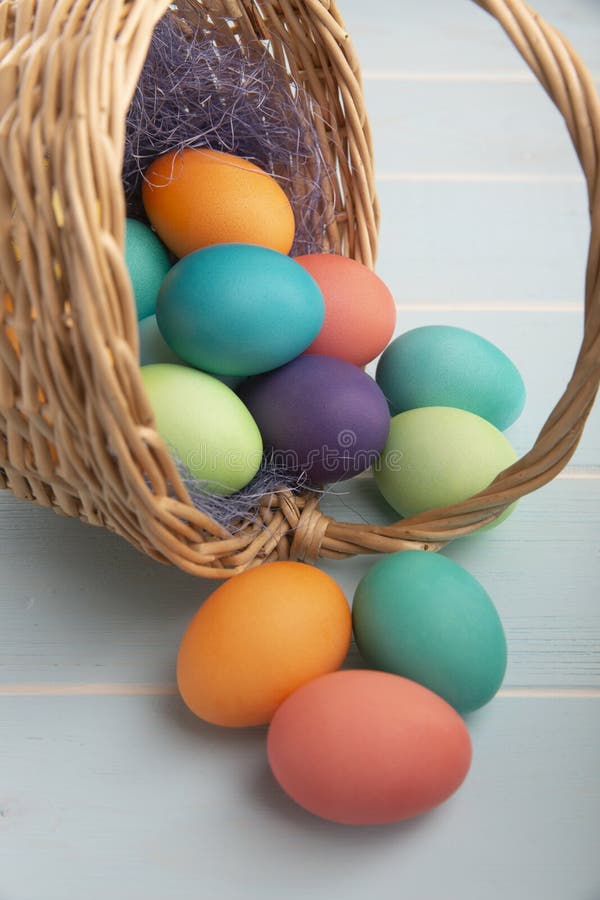 Mezcla de huevos de Pascua brillantes teñidos en a con la cesta con el sisal azul colorido en una superficie azul de madera fotos de archivo libres de regalías Mezcla de huevos de Pascua brillantes teñidos en a con la cesta con el sisal azul colorido en una superficie azul de madera fotos de archivo libres de regalías