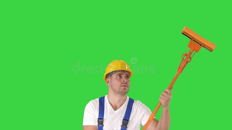 Mi fen? tre adulte de sourire de nettoyage de travailleur avec la racle et sourire? la cam? ra sur un? cran vert, cl? de chroma banque de vidéos