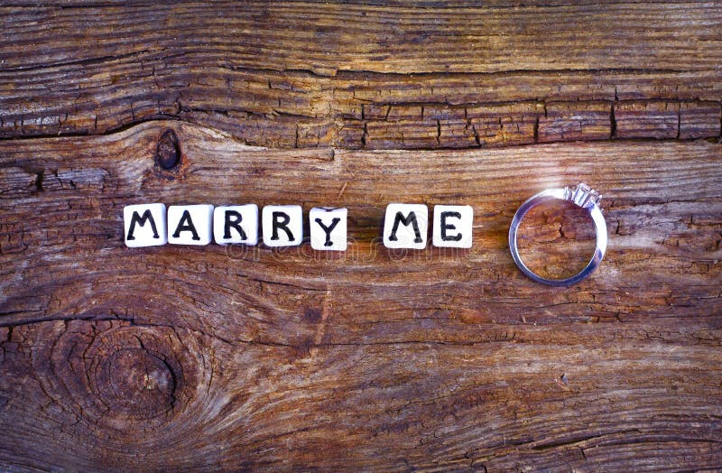 Mi sposerete? Un'offerta del matrimonio su fondo rustico L'espressione “mi sposa “scritto con i piccoli cubi e fede nuziale vicin