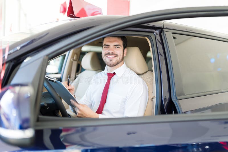 Mi vendeur adulte travaillant dans la salle d'exposition de voiture photographie stock Mi vendeur adulte travaillant dans la salle d'exposition de voiture photographie stock