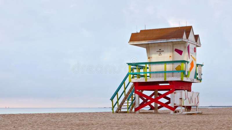 Miami Beach Florida, yellow lifeguard house in a typical colorful Art Deco style at summer day sunrise, with blue sky and Atlantic Ocean in the background. Long exposure and light painting. World famous travel location. Miami Beach Florida, yellow lifeguard house in a typical colorful Art Deco style at summer day sunrise, with blue sky and Atlantic Ocean in the background. Long exposure and light painting. World famous travel location.