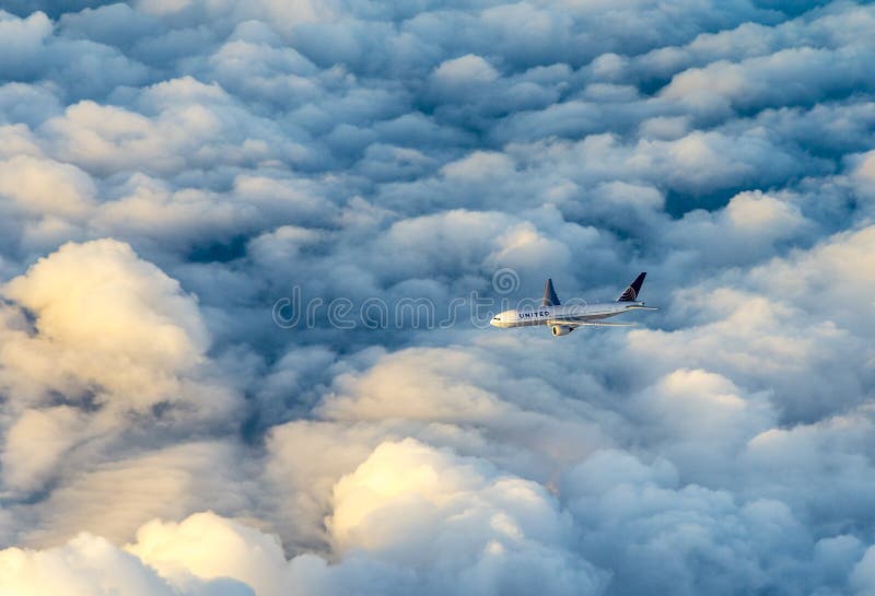 United airlines aircraft flies in the dark clouds with sunlight at the cockpit