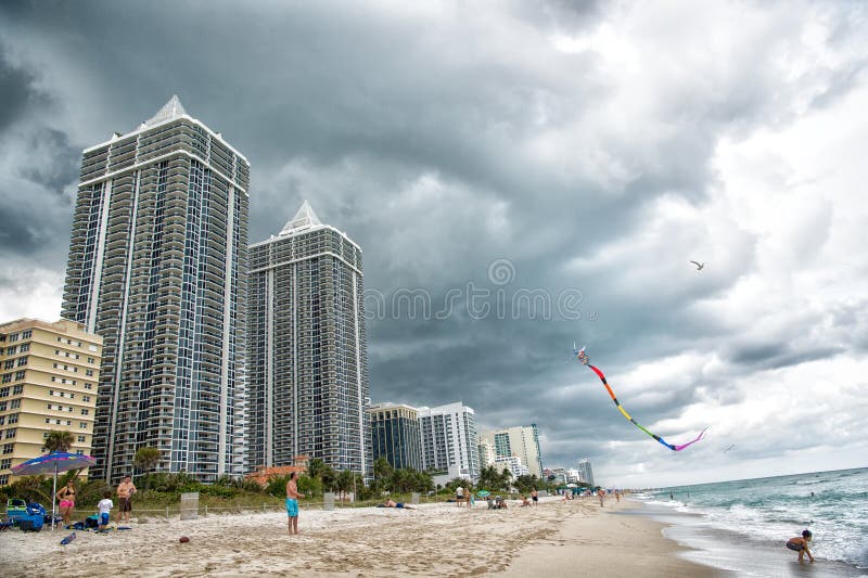 Miami, USA - January 10, 2016: sea beach and kite fly in cloudy sky. south miami beach Architecture and real estate on luxury resort. Summer vacation on sea. Wanderlust or travel. Miami, USA - January 10, 2016: sea beach and kite fly in cloudy sky. south miami beach Architecture and real estate on luxury resort. Summer vacation on sea. Wanderlust or travel.