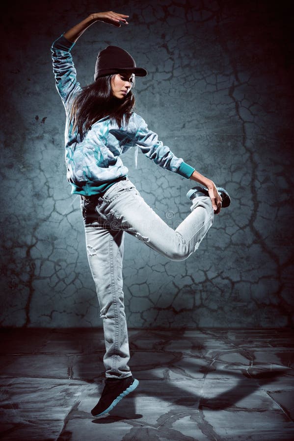 Urban hip hop dancer with grunge concrete wall background texture jumping and dancing with hoodie. Urban hip hop dancer with grunge concrete wall background texture jumping and dancing with hoodie