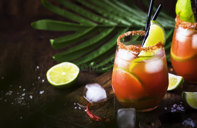 Michelada - Mexican alcoholic cocktail with beer, lime juice, tomato juice, spicy sauce and spices, vintage wooden background