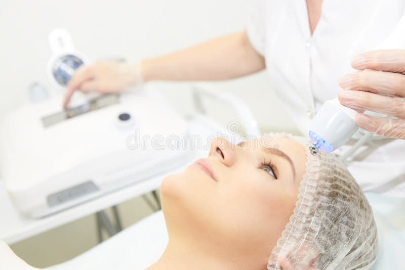 Microcurrent facial dermatology procedure. Model. Aesthetic radiofrequency treatment. Micro current cosmetology massage