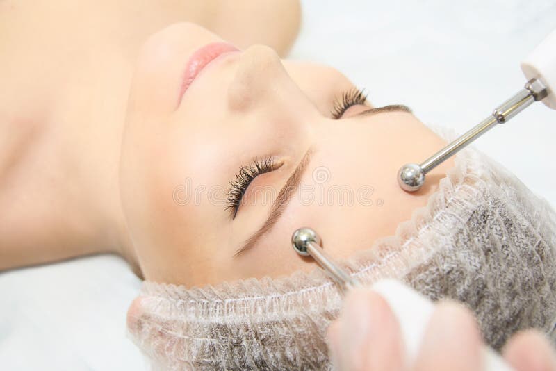 Microcurrent facial dermatology procedure. Model. Aesthetic radiofrequency treatment. Micro current cosmetology massage