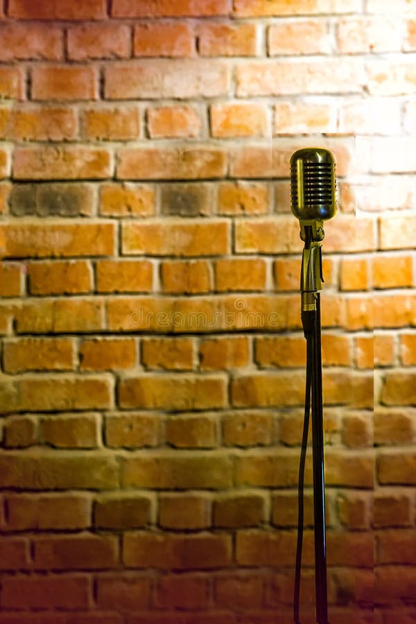 Microfono pronto sul palco contro un muro di mattoni pronto per l'attore karaoke