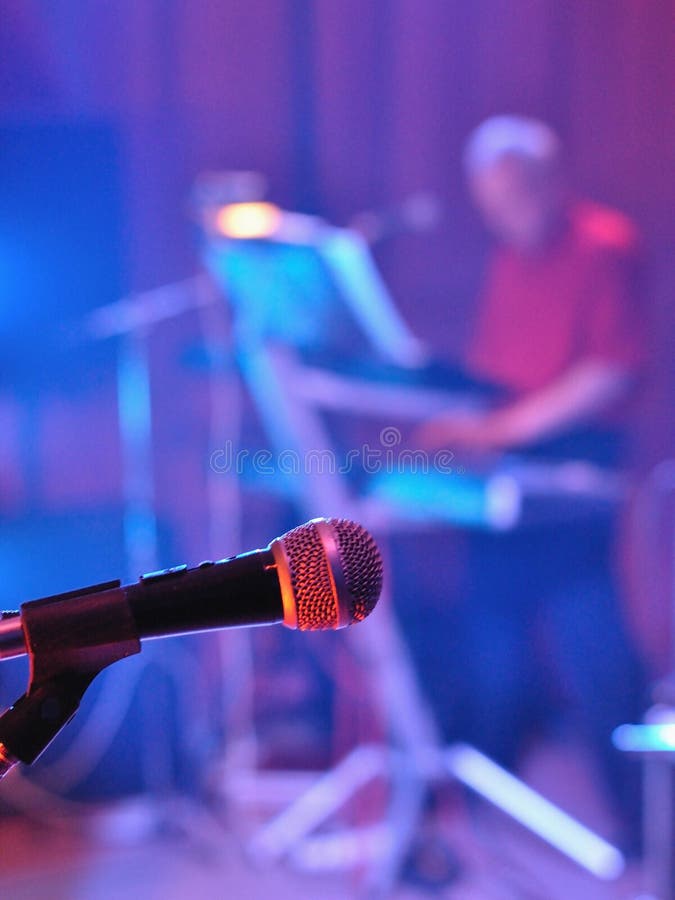Microphone avec le pianiste brouillé à l'arrière-plan photographie stock libre de droits Microphone avec le pianiste brouillé à l'arrière-plan photographie stock libre de droits