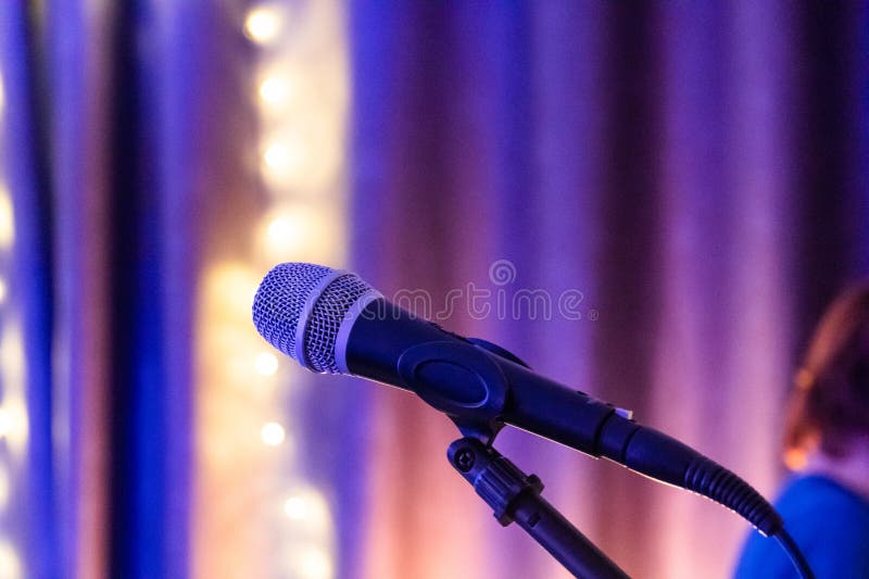Microphone and stage light. Public performance on stage Microphone on stage against a background of auditorium. Shallow depth of stock photos