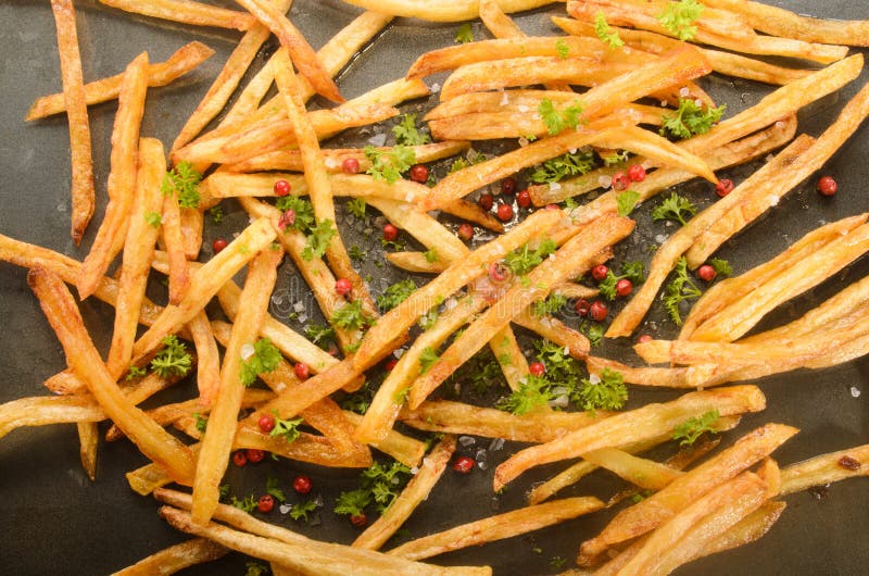 Batatas fritas com pimentão vermelho, sal marinho e salsa num tabuleiro de forno fotos de stock