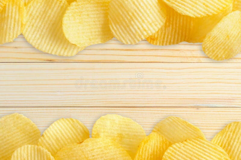 Microplaquetas de batata na tabela de madeira com espaço da cópia imagens de stock Microplaquetas de batata na tabela de madeira com espaço da cópia imagens de stock
