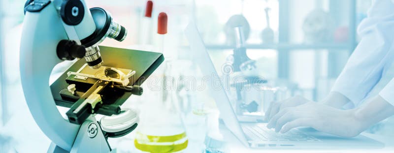 Microscope in lab. Close-up shot of examining test sample under the microscope in laboratory. scientist working with laptop stock photo