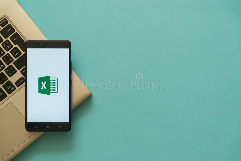 Microsoft office excel logo on smartphone placed on laptop keyboard.