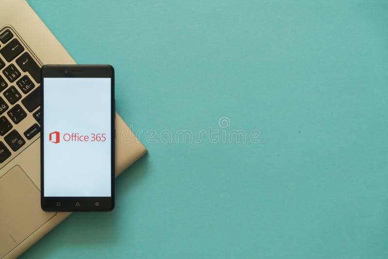 Microsoft office 365 logo on smartphone placed on laptop keyboard.